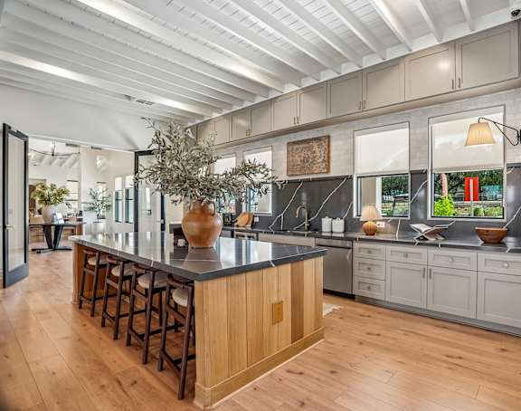 A kitchen with a long island and wooden floors.