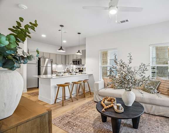 A modern living room with a kitchen in the background.