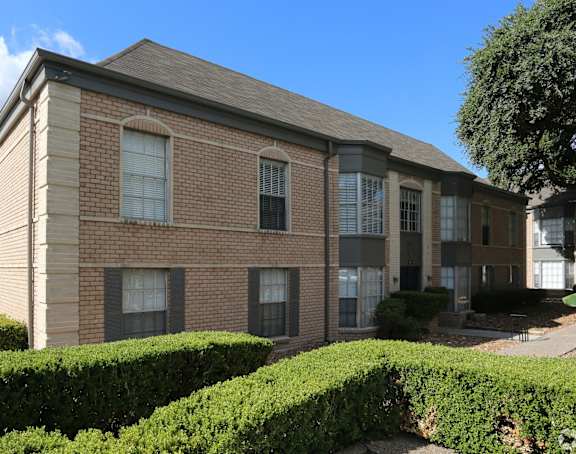 a brick building with hedges in front of it