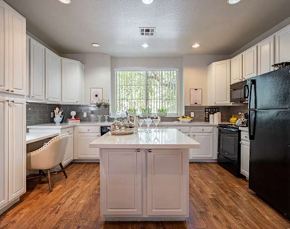 A kitchen with a black refrigerator and white cabinets.at Palazzo Townhomes, Phoenix, AZ 85008