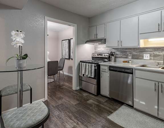 a kitchen with white cabinets and stainless steel appliances and a dining table at Tucker Square, Stone Mountain
