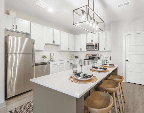 A modern kitchen with a large island and wooden chairs.