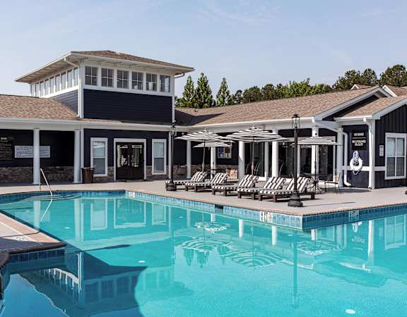 a swimming pool with lounge chairs and umbrellas in front of a building