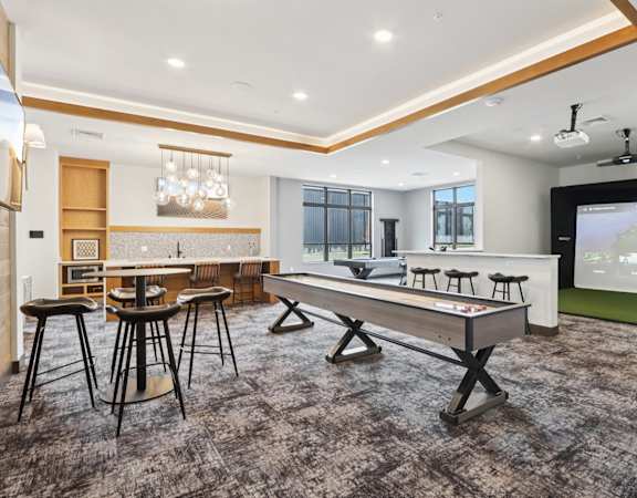 A room with a long table and chairs, a bar area, and a projection screen.