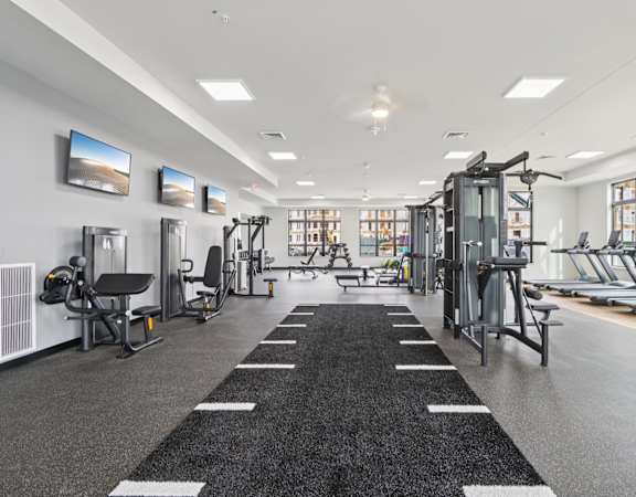 A spacious gym with a variety of equipment and a large mirror on the wall.