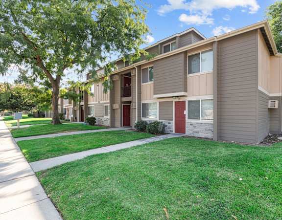 A row of townhouses with green lawns in front.