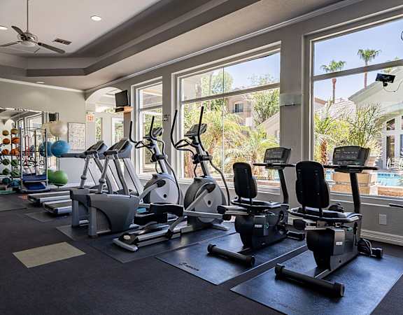 A gym with a row of treadmills and elliptical machines.at Palazzo Townhomes, Phoenix, AZ 85008