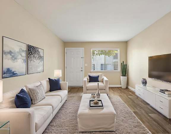 A living room with a white couch, a coffee table, and a television.