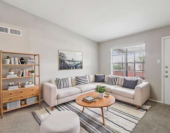 A living room with a white couch, a wooden coffee table, and a bookshelf.