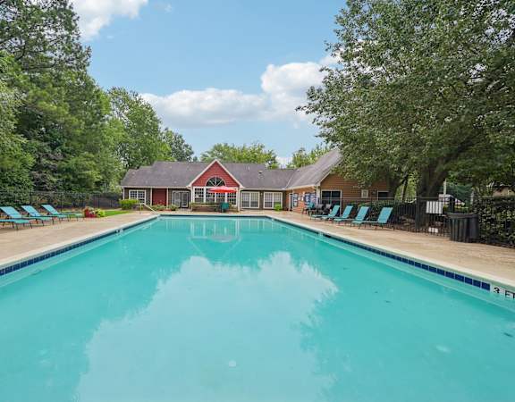 A large swimming pool surrounded by trees and lounge chairs.