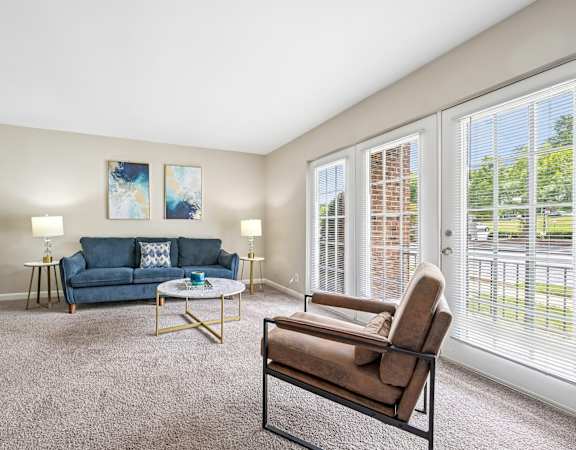 A living room with a blue couch, a chair, and two lamps.