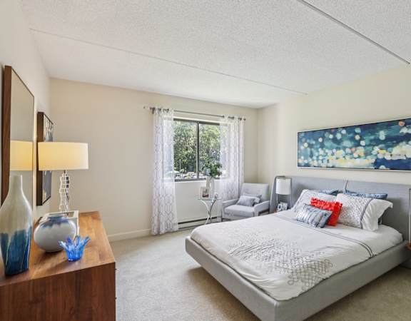 A bedroom with a large bed and a painting on the wall.