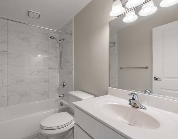A white bathroom with a marble tile shower.