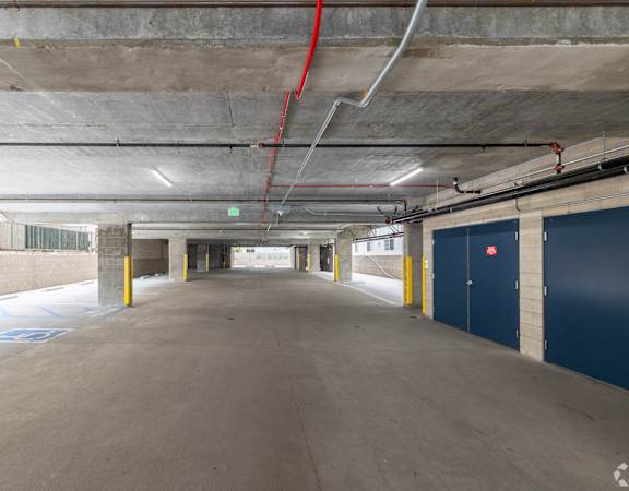 A long, empty parking garage with a red hose running along the ceiling.