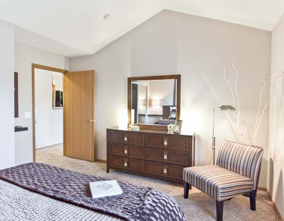 a bedroom with a bed and a chair and a dresser