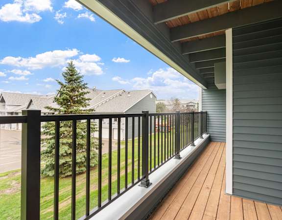 A balcony with a black railing and a wooden floor.