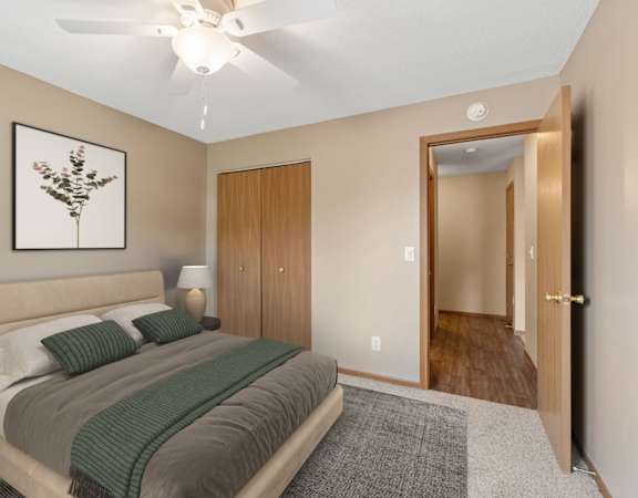 A bedroom with a bed, a ceiling fan, and a door.