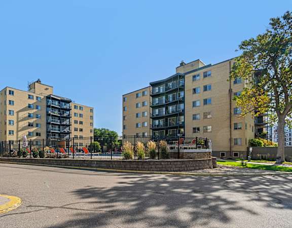 Two apartment buildings with a parking lot in front.