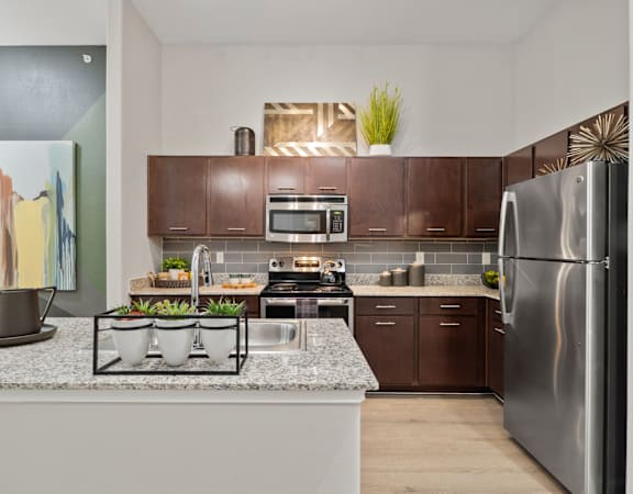 A modern kitchen with a white countertop and stainless steel appliances.