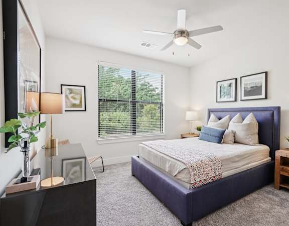 A bedroom with a large bed and a ceiling fan.