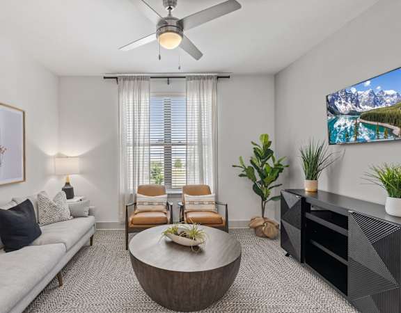 A living room with a grey sofa, a coffee table, a TV, and a painting on the wall.