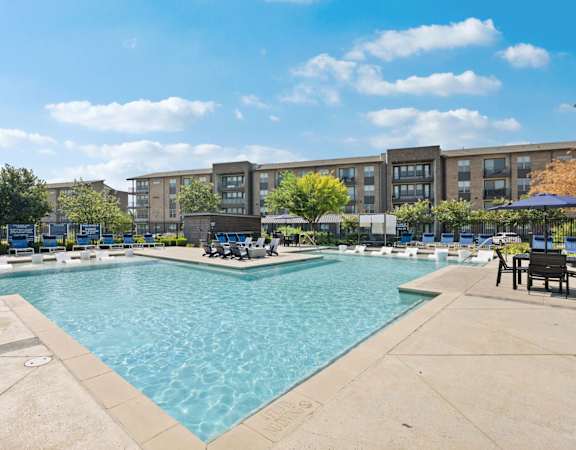 A large outdoor swimming pool with a building in the background.