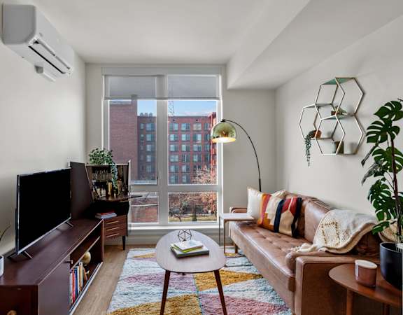 a living area with a large window, a couch, a coffee table, and a tv