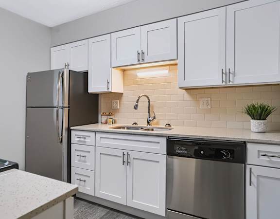 A kitchen with white cabinets and a black refrigerator.