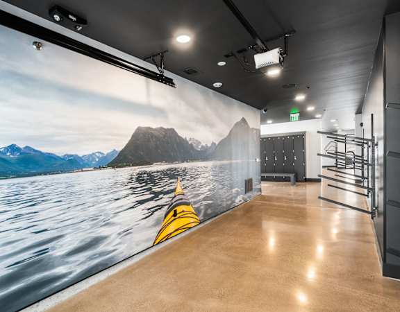 A wall mural of a kayak on a lake with mountains in the background.