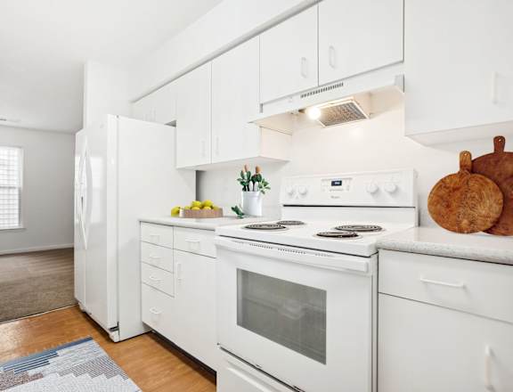 A white kitchen with a refrigerator, oven, and stove.