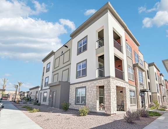 an apartment building with a sidewalk in front of it at The Maddox Luxury Apartment Homes, Buckeye, AZ, 85326