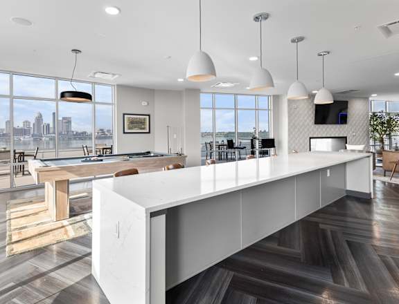 A modern kitchen with a long white island and a view of the city.