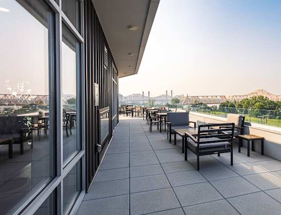 A patio with tables and chairs overlooking a bridge.
