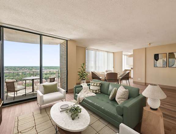 A living room with a green couch and a table with a plant on it.