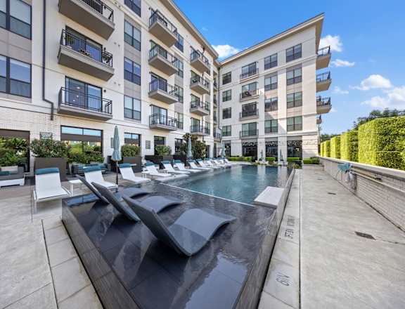A modern apartment complex with a pool in the foreground.