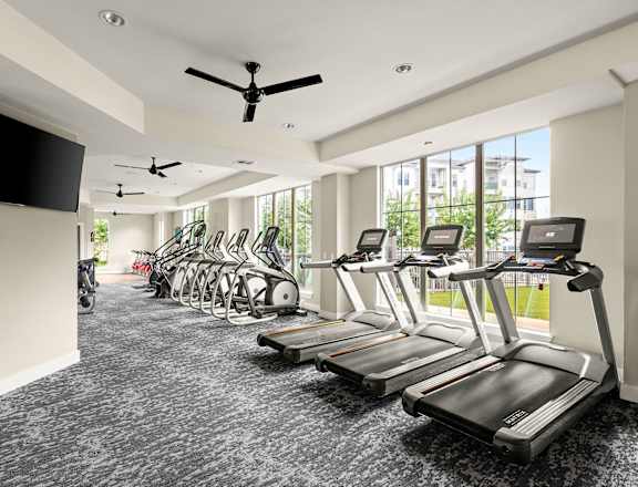 a gym with cardio machines and a tv