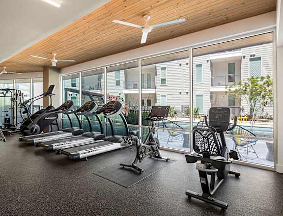 A gym with a variety of equipment including treadmills, elliptical machines, and weights.