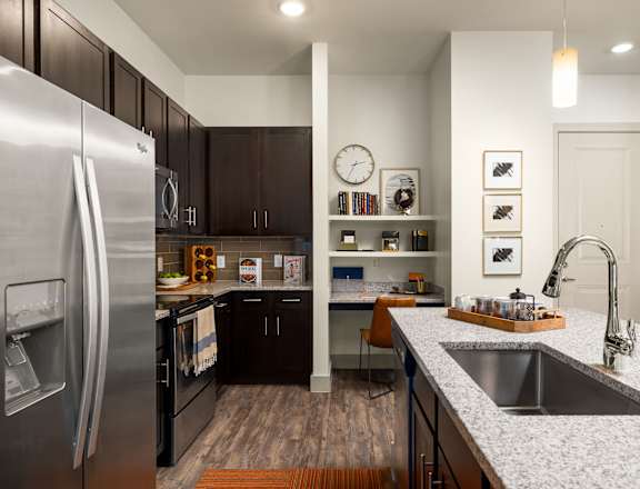 A modern kitchen with a stainless steel refrigerator and a marble countertop.
