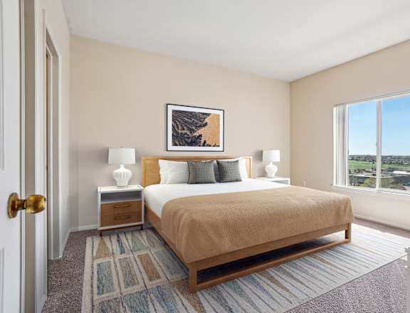 A bedroom with a bed, nightstands, and a window overlooking a landscape.
