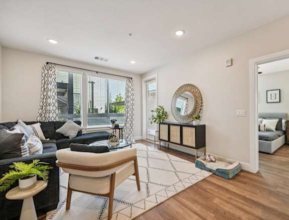 A modern living room with a black couch and a glass coffee table.
