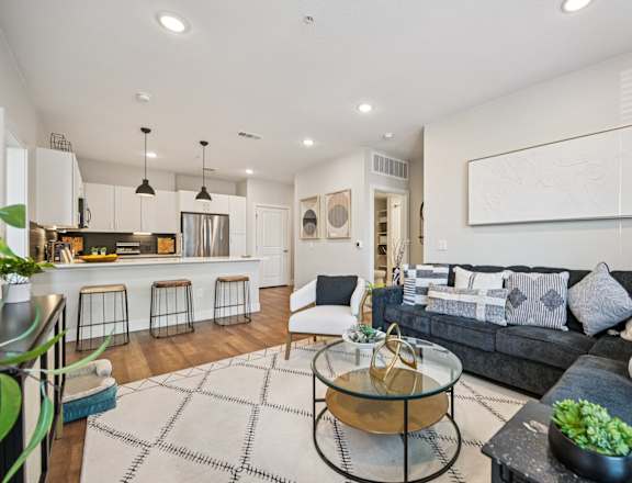 A modern living room with a grey couch and a glass coffee table.