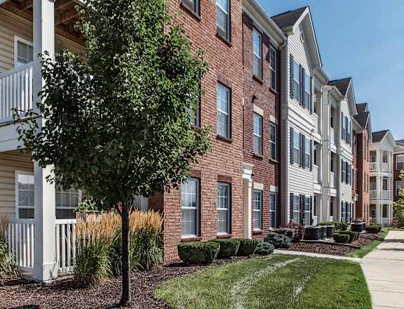 a brick apartment building with a tree in front of it at Brickshire Apartments, Merrillville