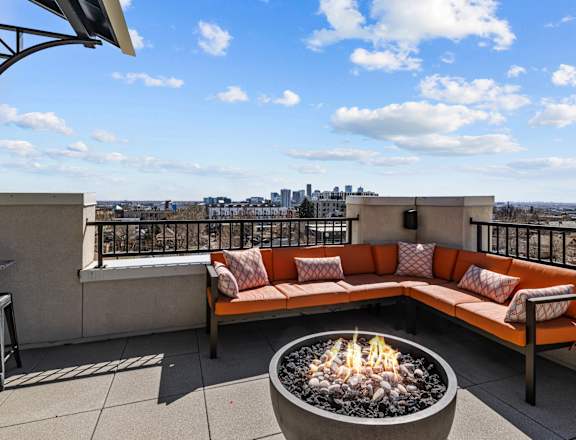 A patio with a fire pit and a view of the city.