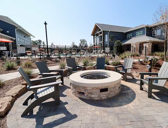 an outdoor fire pit with chairs and a house in the background at The Crest at Acworth, Acworth, 30102
