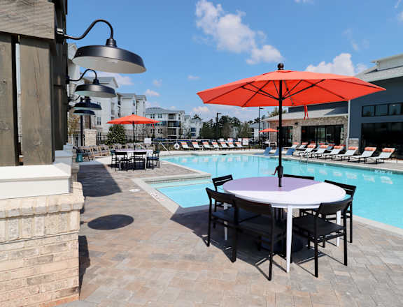 a swimming pool with a table with umbrellas and chairs at The Crest at Acworth, Acworth