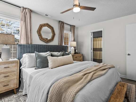 A bedroom with a large bed, a ceiling fan, and a mirror on the wall at West Oak Apartments, Wake Forest, 27587