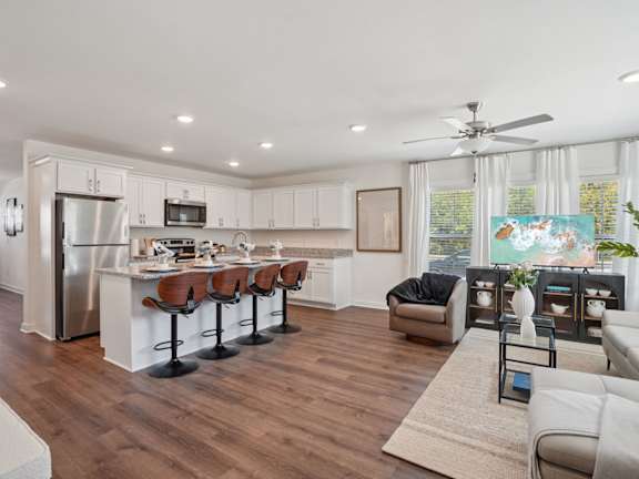 A modern kitchen with white cabinets and a wooden floor.