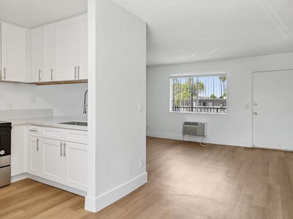 A kitchen with a table and chairs in front of a fridge and cabinets.