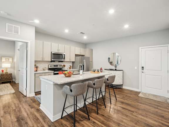A kitchen with a white island and wooden floors at AxisOne Apartments in Stuart, FL 34994