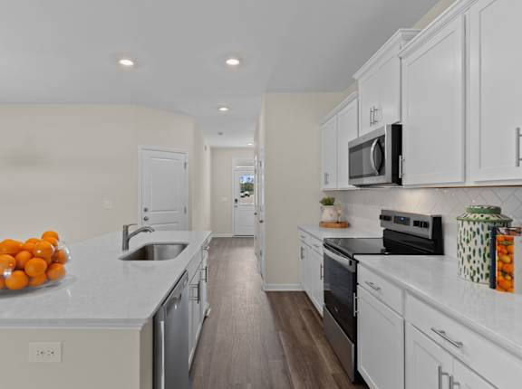 A kitchen with white cabinets and a countertop with oranges on it.